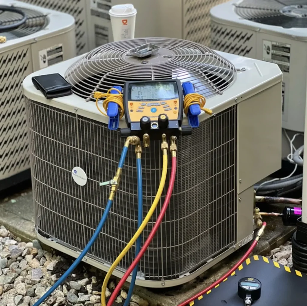 Digital manifold gauges connected to an outdoor AC condenser during repair