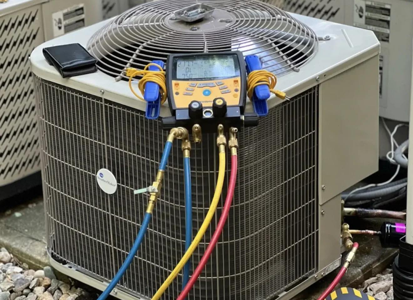 Digital manifold gauges connected to an outdoor AC condenser during repair