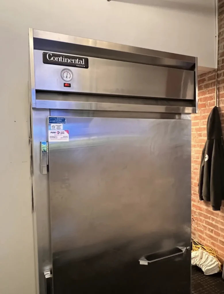 Stainless commercial upright refrigerator installed in a food-service workspace