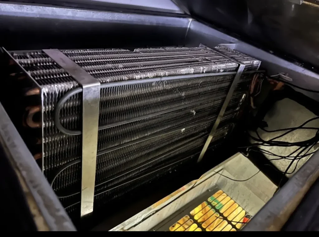 Exposed indoor evaporator coil being inspected inside HVAC equipment
