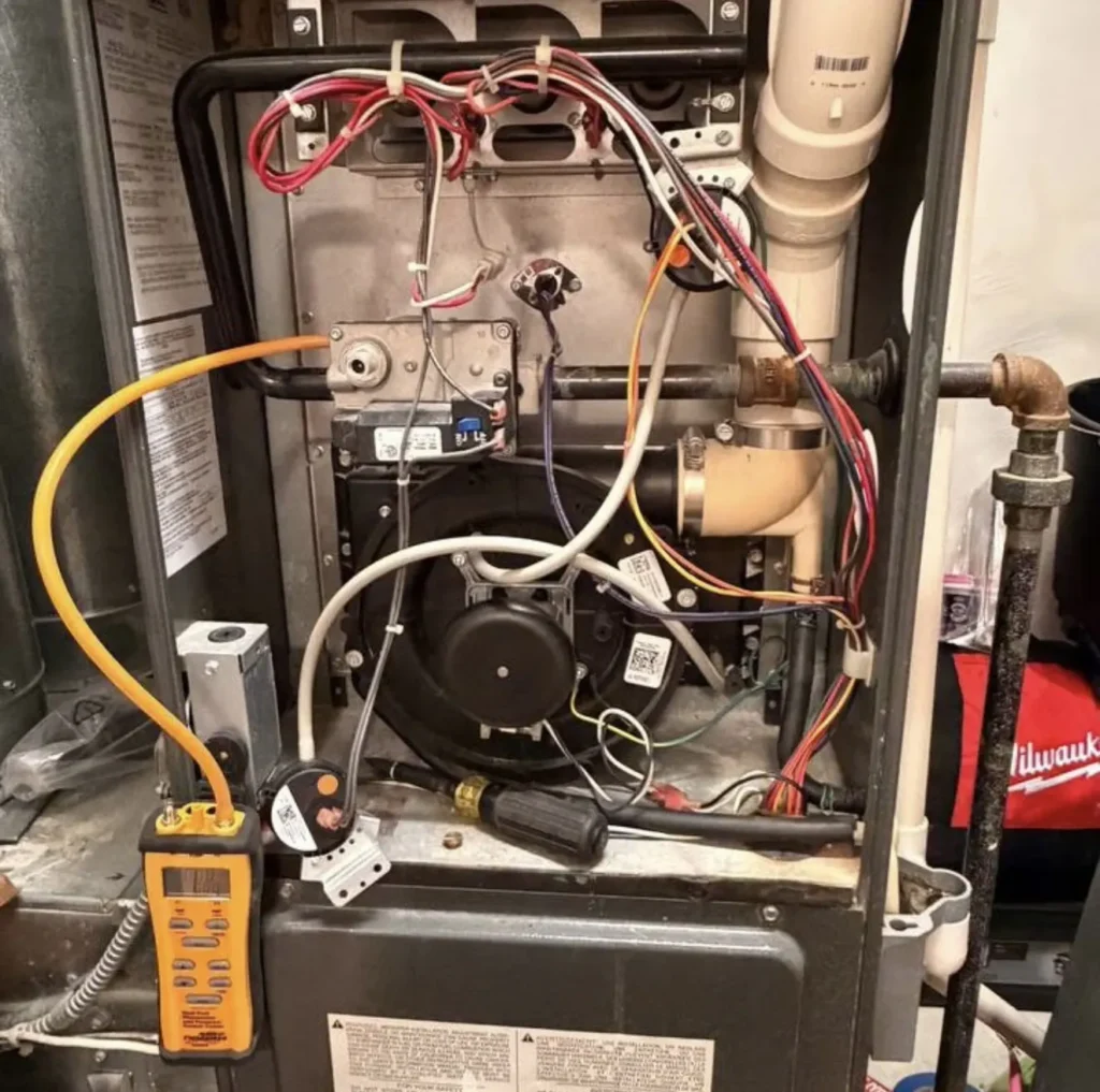 Open gas furnace with digital diagnostic instrument connected during service