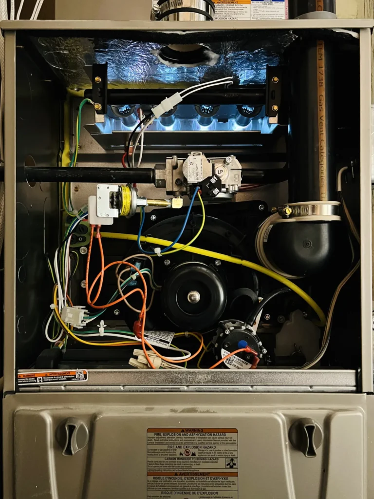 Open gas furnace showing burners, inducer assembly, controls, and service instruments