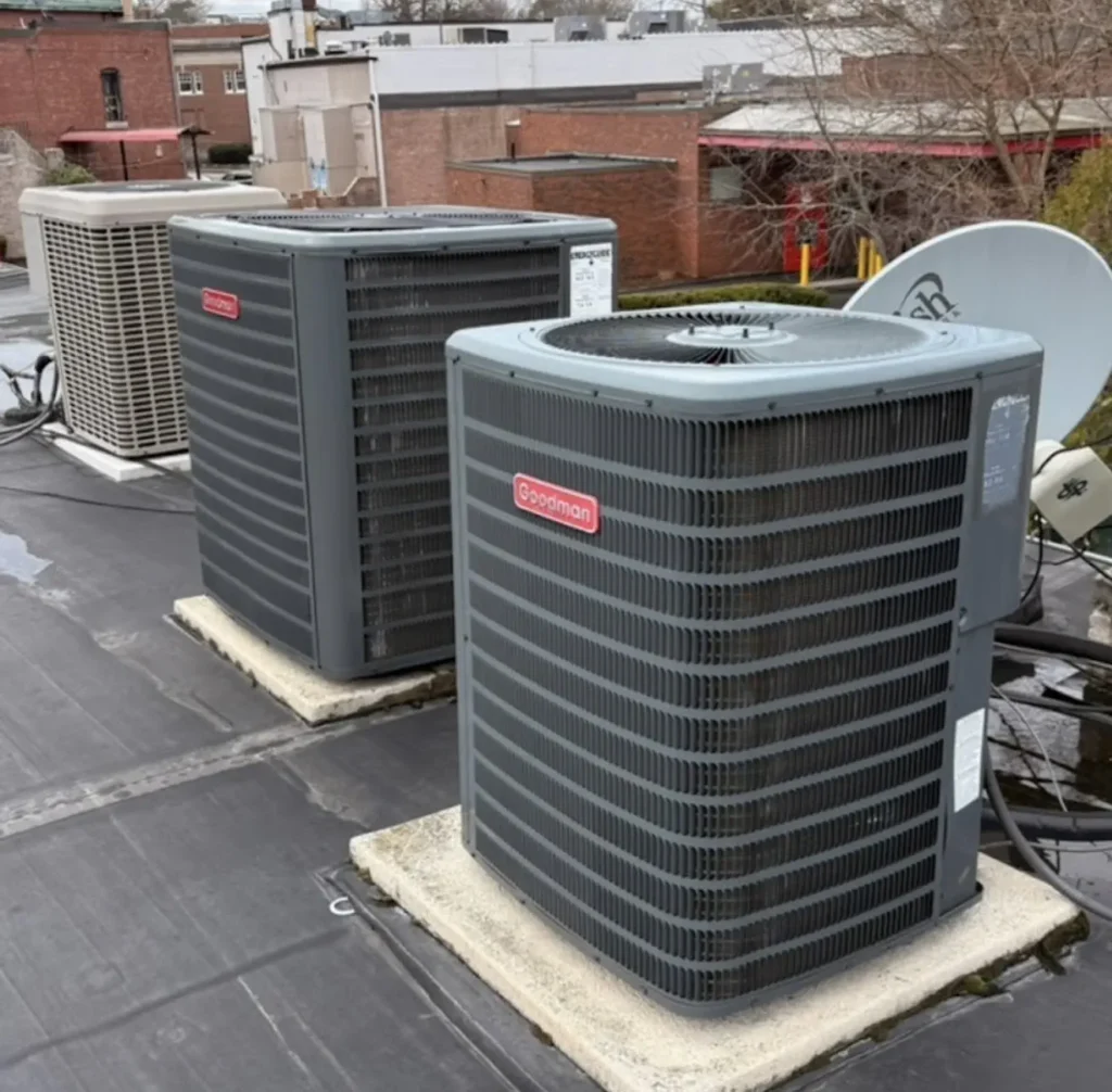 Two Goodman outdoor heat-pump condensers installed on rooftop equipment pads