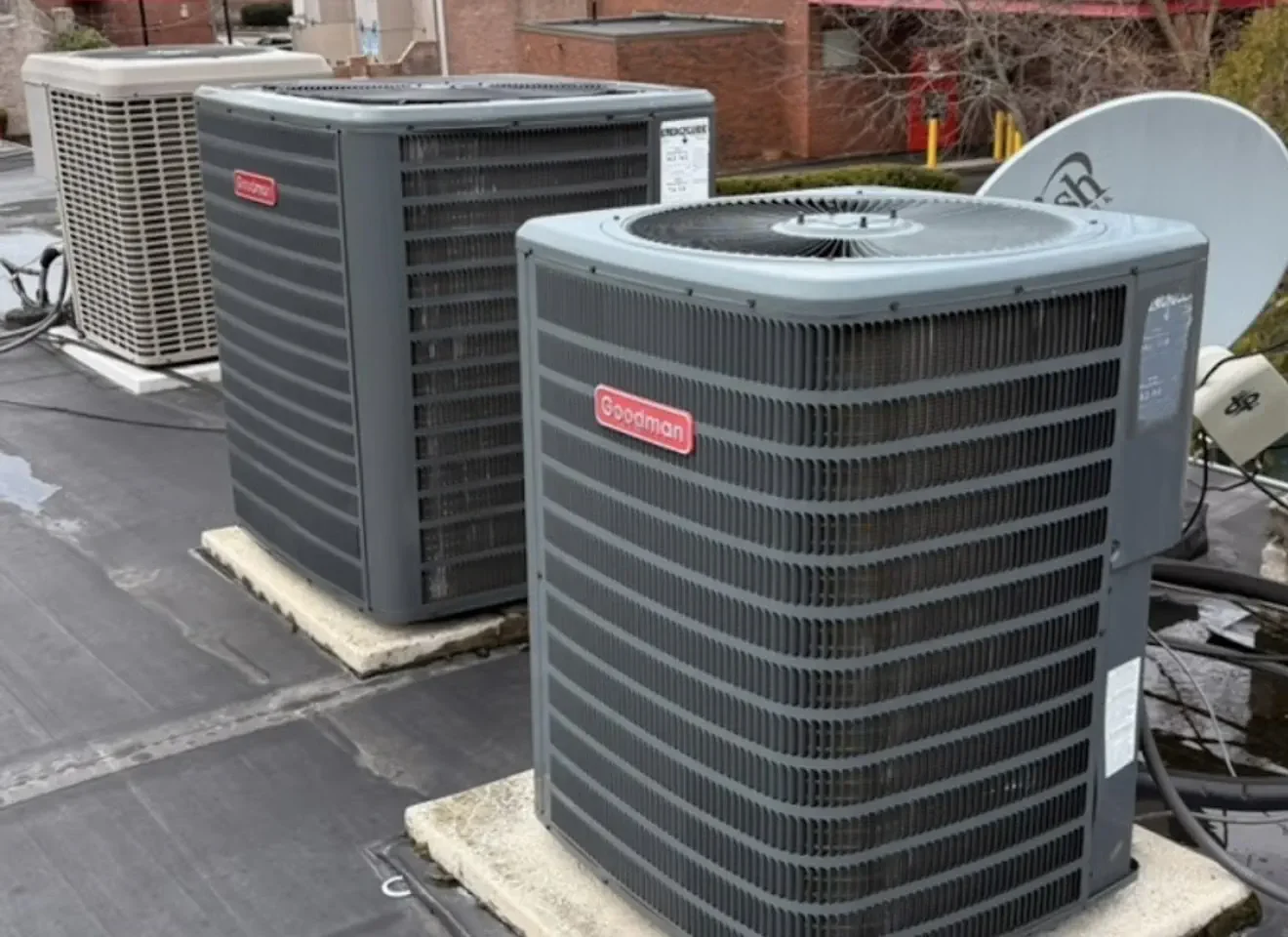 Two Goodman outdoor heat-pump condensers installed on rooftop equipment pads