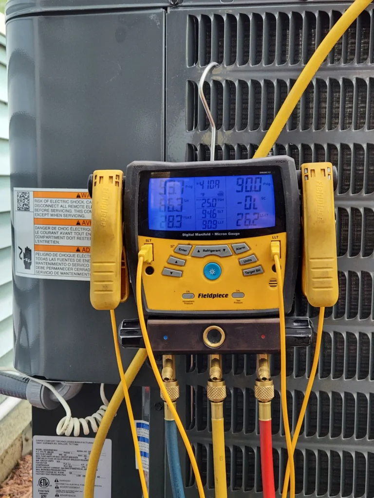 Digital manifold gauges connected to an outdoor heat pump during refrigerant testing