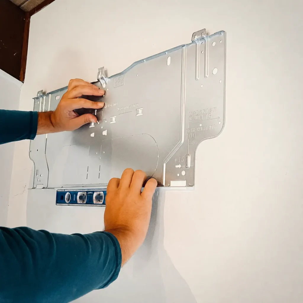 HVAC technician leveling a mounting bracket for a ductless mini-split indoor unit