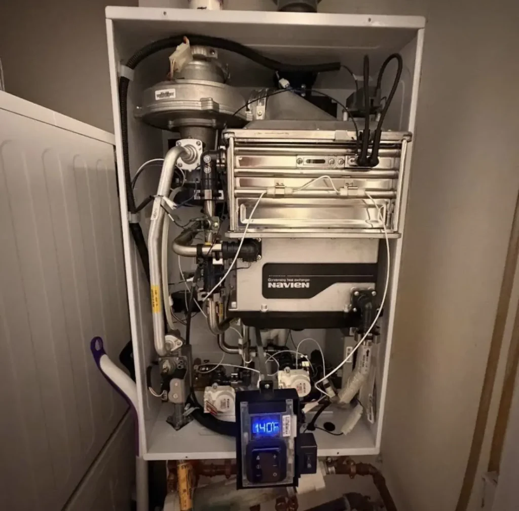 Open wall-mounted Navien boiler showing internal heat exchanger and controls
