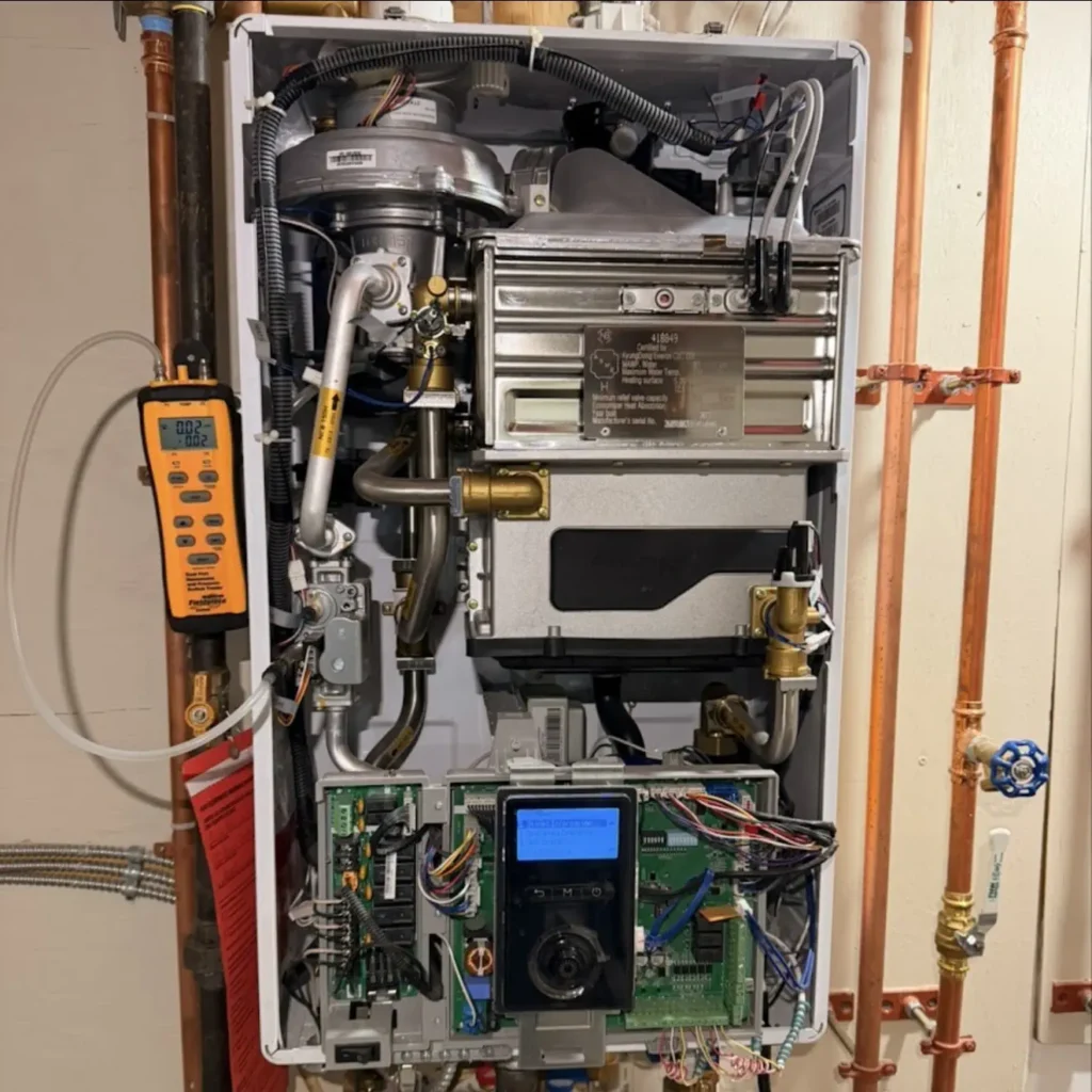 Open Navien combi boiler being tested with a digital multimeter