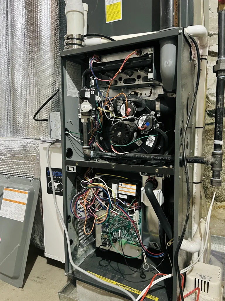 Residential furnace opened to expose burners, blower, wiring, and control components