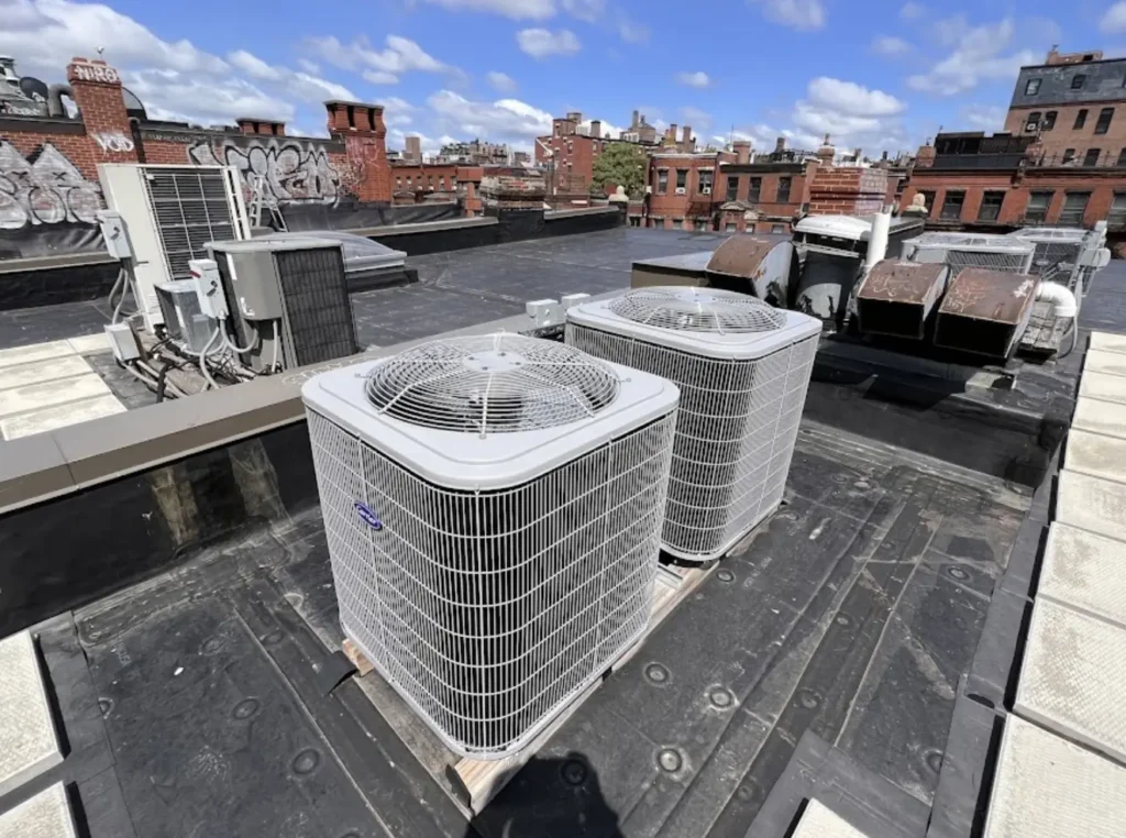 Several outdoor AC condensers installed and serviced on a Boston rooftop