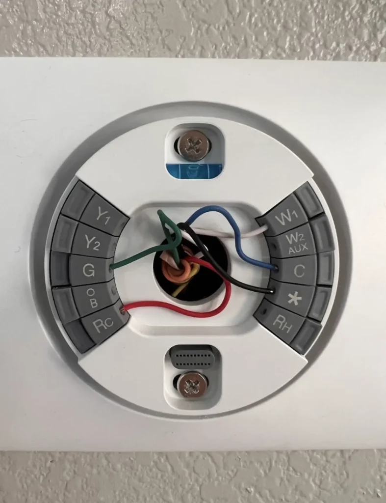 Low-voltage HVAC wires connected to a round thermostat wall base