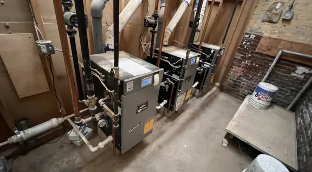 Two residential heating boilers installed side by side with hydronic piping